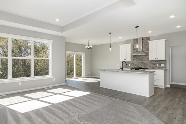 kitchen featuring backsplash, wall chimney exhaust hood, dark wood-type flooring, pendant lighting, and white cabinetry