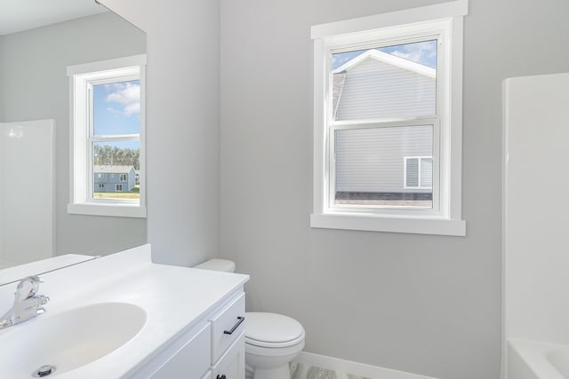 bathroom featuring vanity, a bathtub, toilet, and plenty of natural light