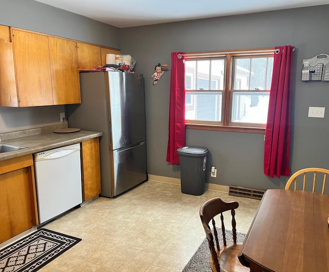 11159 Steamboat Loop NW, Walker, MN 56484 - kitchen with dishwasher, freestanding refrigerator, brown cabinetry, light flooring, and light countertops