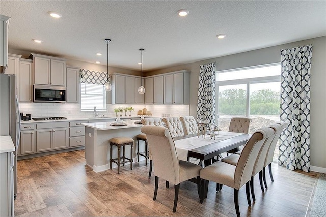 dining area with a textured ceiling, light wood-type flooring, and sink