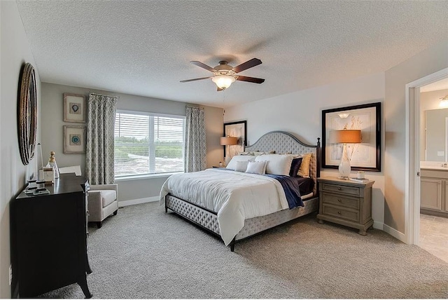 carpeted bedroom with a textured ceiling, ensuite bathroom, and ceiling fan