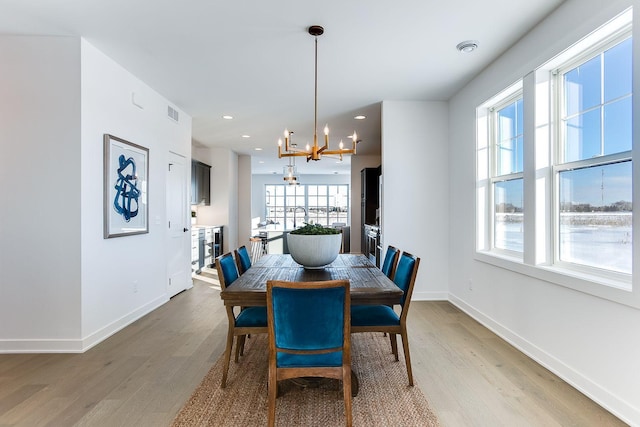 dining area featuring light wood-type flooring, a wealth of natural light, and a chandelier