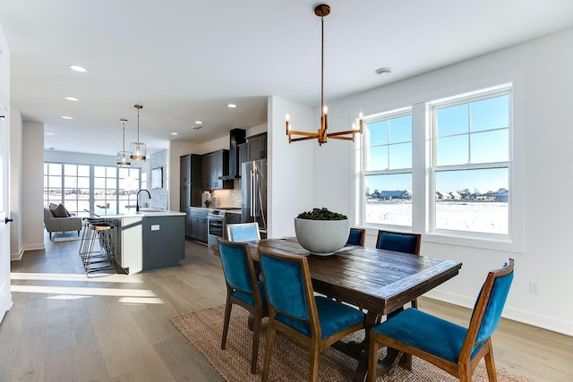 dining space with a chandelier, light hardwood / wood-style floors, plenty of natural light, and sink