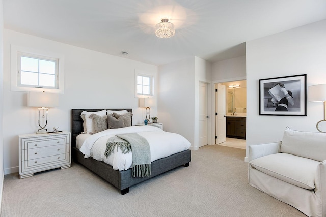 bedroom with multiple windows, ensuite bathroom, and light colored carpet