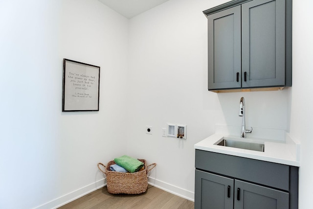 washroom with cabinets, sink, hookup for a washing machine, hookup for an electric dryer, and light hardwood / wood-style floors