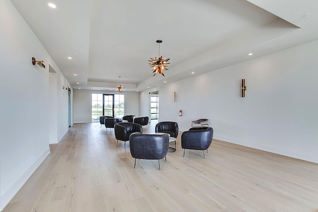 living room featuring light wood-type flooring, a tray ceiling, and ceiling fan