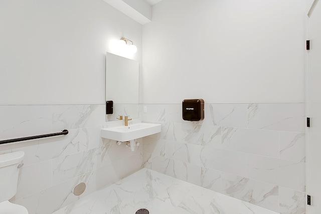 bathroom featuring toilet, sink, and tile walls