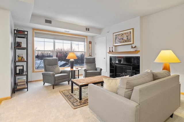 living room featuring a tile fireplace and light colored carpet