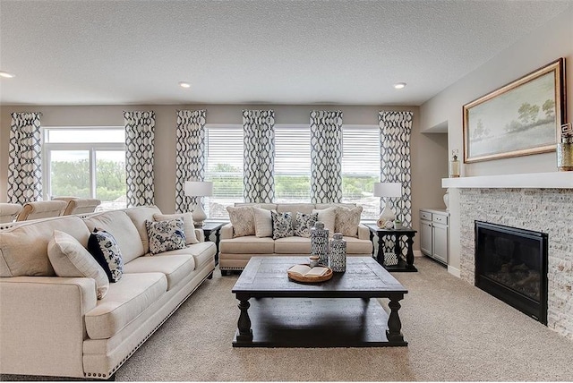 carpeted living room with a fireplace, a textured ceiling, and plenty of natural light