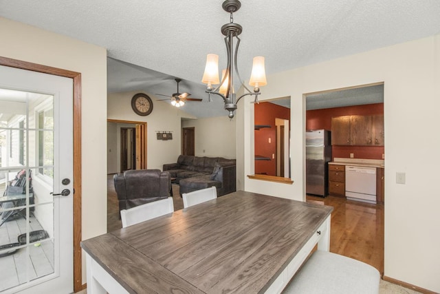 dining room featuring wood-type flooring, ceiling fan with notable chandelier, and a textured ceiling