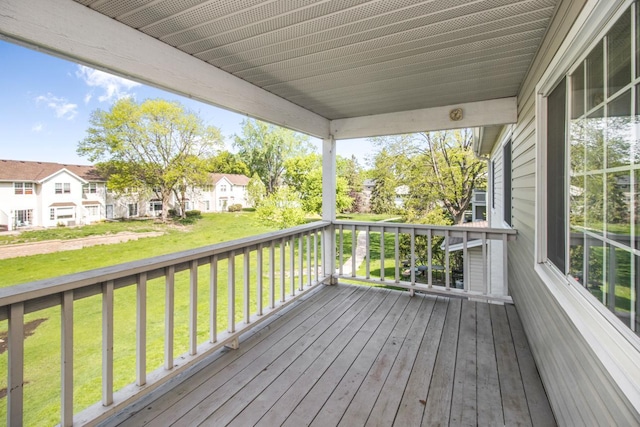 wooden terrace featuring a lawn and covered porch