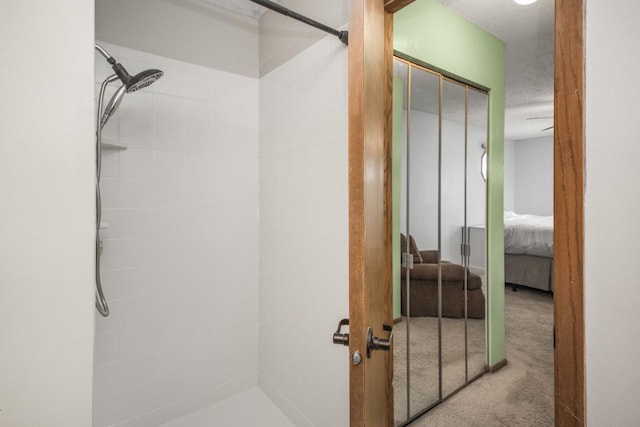 bathroom with a tile shower and a textured ceiling