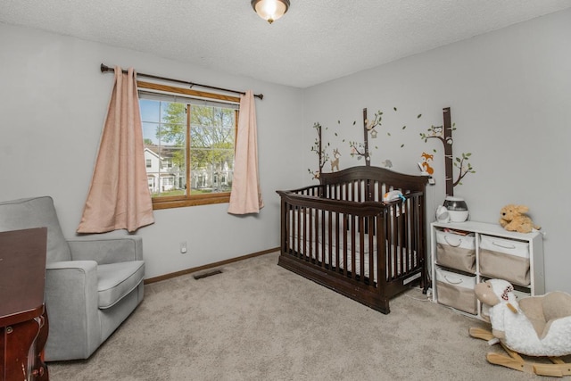 carpeted bedroom with a crib and a textured ceiling