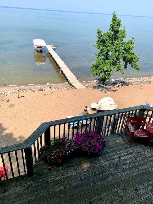 view of dock featuring a water view and a beach view