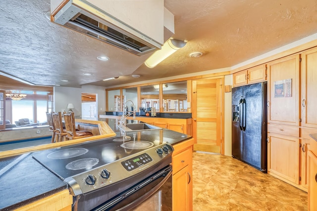 kitchen with stainless steel range with electric cooktop, light brown cabinetry, sink, premium range hood, and black fridge