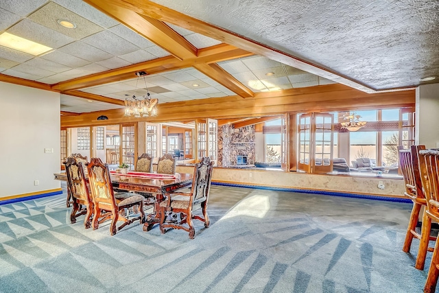 carpeted dining area featuring a stone fireplace, beamed ceiling, an inviting chandelier, and coffered ceiling