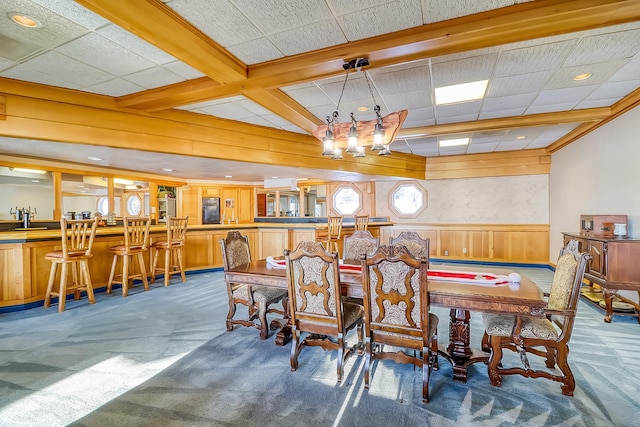 dining space featuring wood walls, beam ceiling, and dark carpet