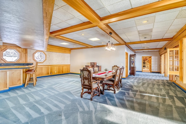 dining area featuring dark carpet, beam ceiling, a notable chandelier, and coffered ceiling