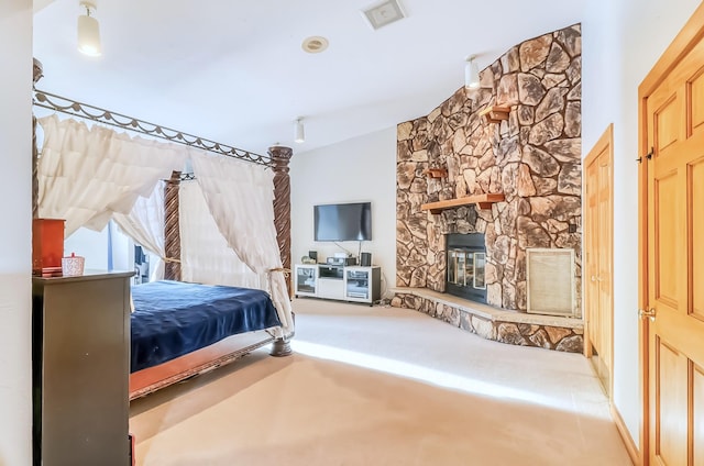 bedroom with carpet floors and a stone fireplace