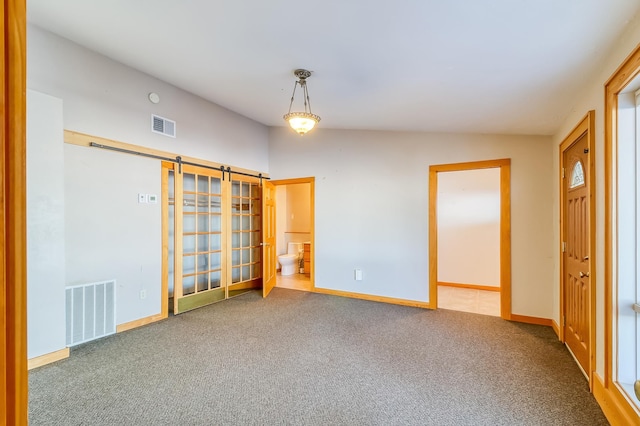 carpeted spare room with lofted ceiling and a barn door