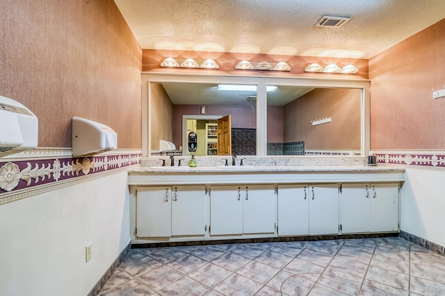 bathroom with a textured ceiling, tile patterned floors, and vanity