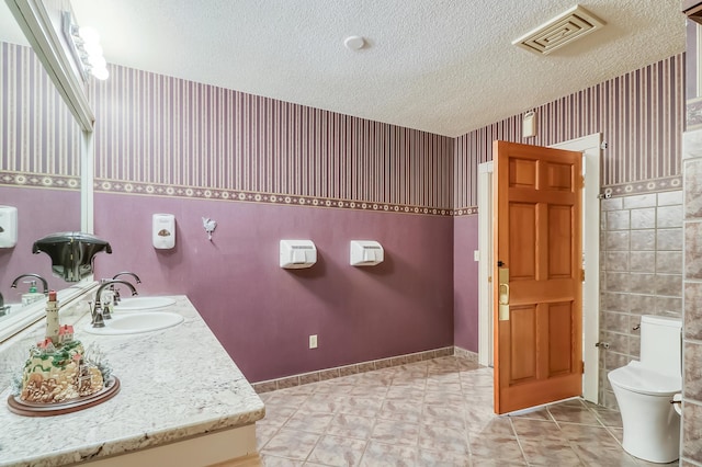 bathroom with a textured ceiling, toilet, vanity, and tile patterned flooring