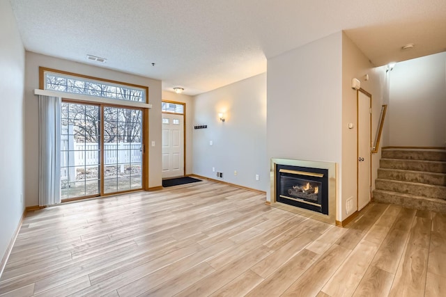 unfurnished living room with light hardwood / wood-style floors and a textured ceiling