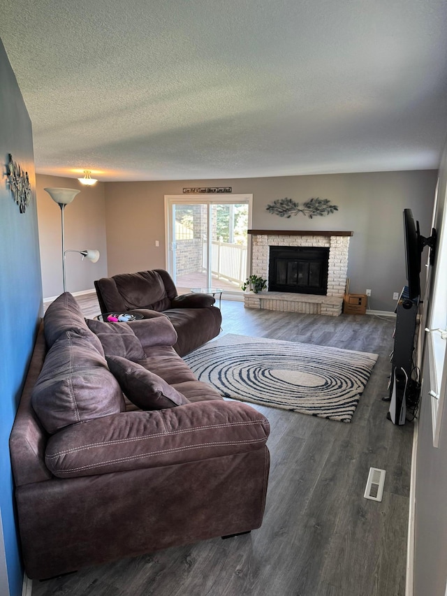 living room with a fireplace, dark wood-type flooring, and a textured ceiling