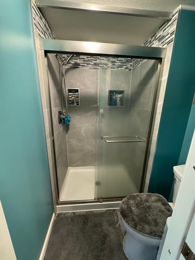 bathroom with toilet and a shower with shower door