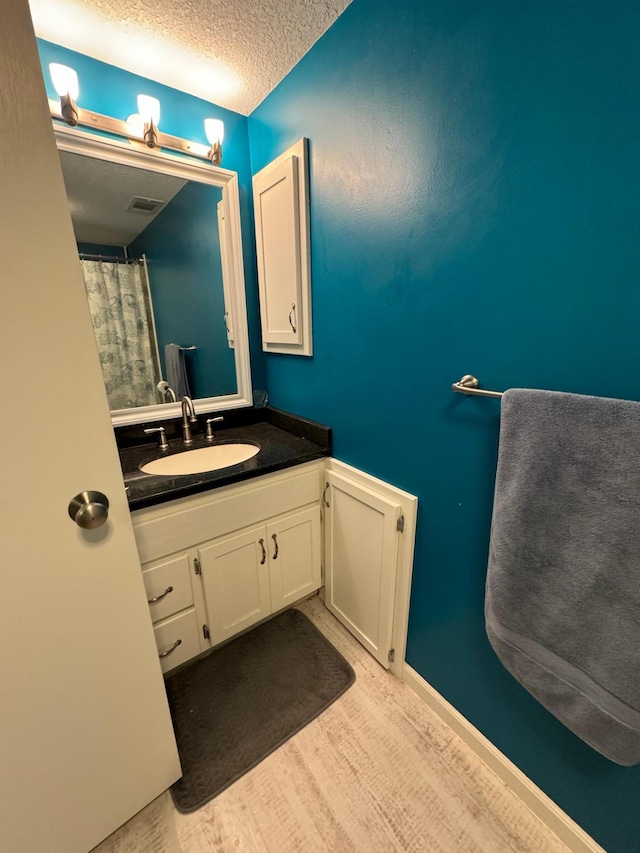 bathroom with a textured ceiling, vanity, and hardwood / wood-style floors