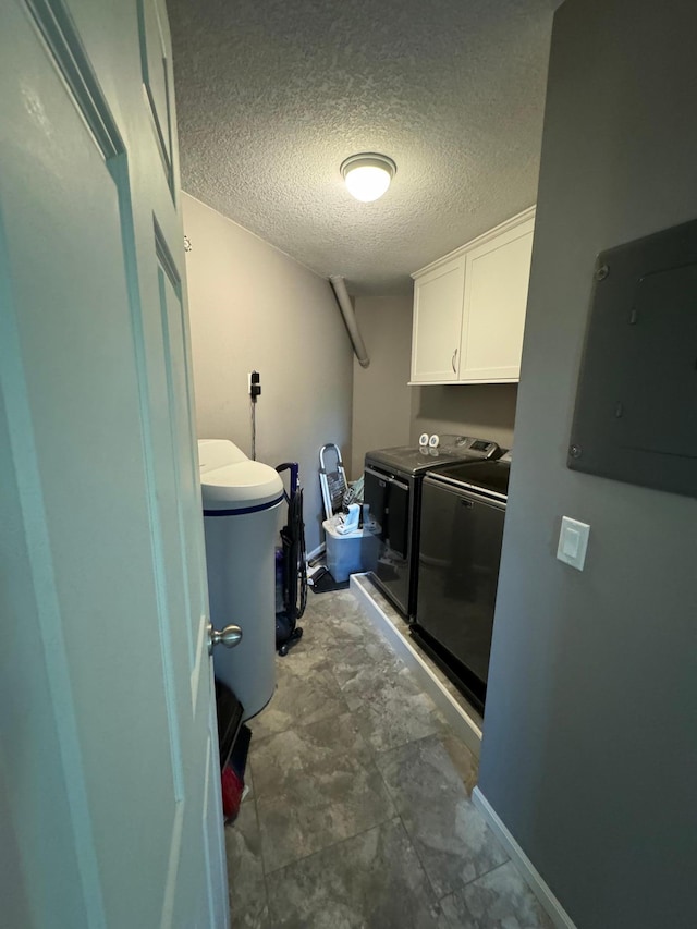 clothes washing area featuring separate washer and dryer, electric panel, cabinets, and a textured ceiling