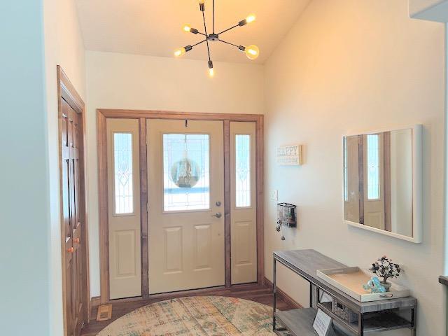 entryway featuring hardwood / wood-style floors, vaulted ceiling, and a notable chandelier