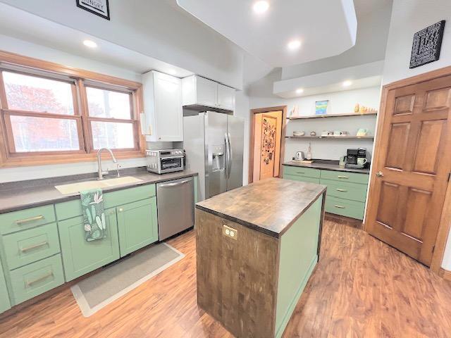 kitchen with a center island, sink, light hardwood / wood-style floors, white cabinetry, and stainless steel appliances