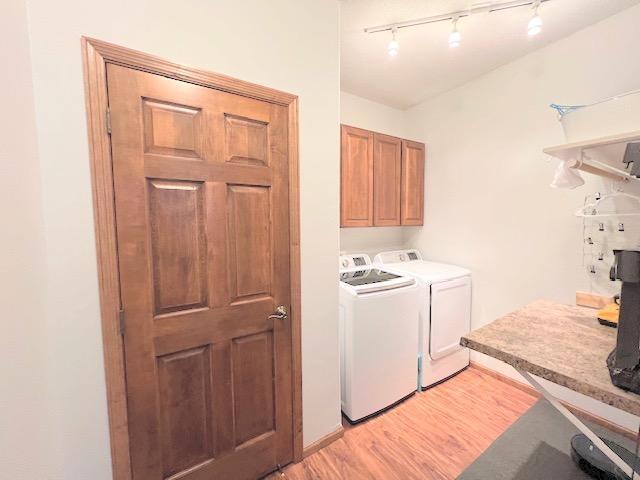 laundry area with separate washer and dryer, light hardwood / wood-style flooring, and cabinets