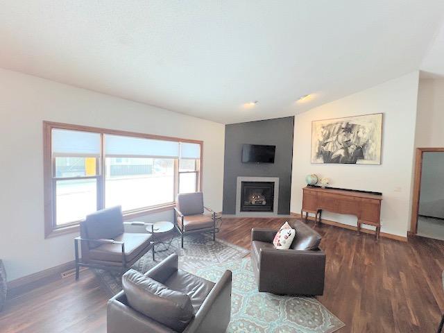 living room with dark hardwood / wood-style flooring and vaulted ceiling