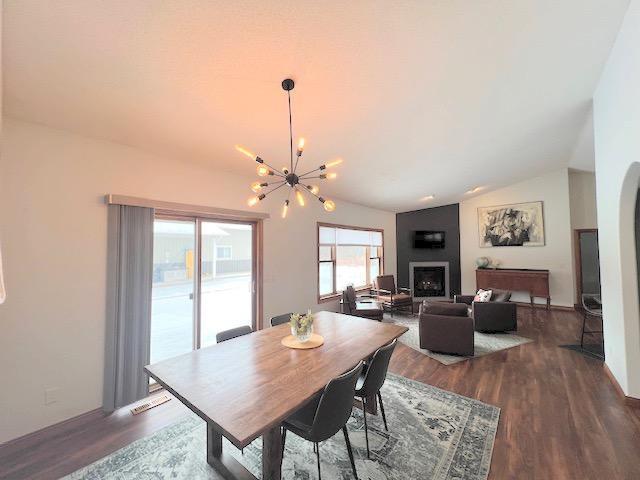 dining area featuring dark wood-type flooring, an inviting chandelier, and lofted ceiling