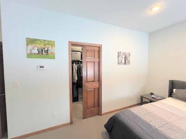 bedroom with light carpet, a walk in closet, and a closet