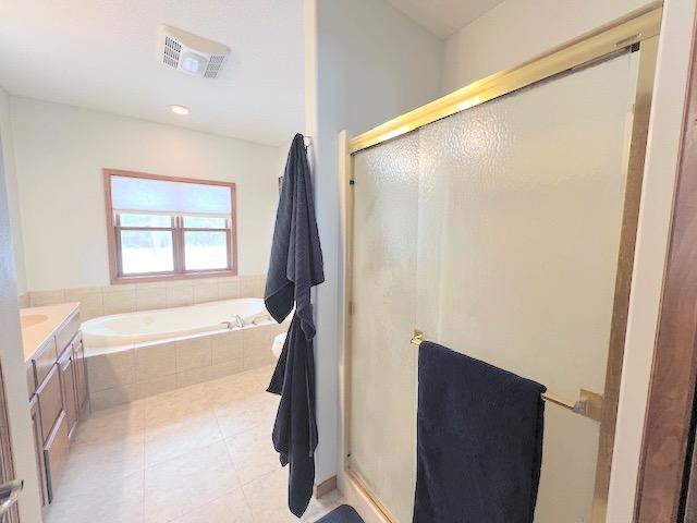 bathroom featuring tile patterned floors, vanity, and shower with separate bathtub