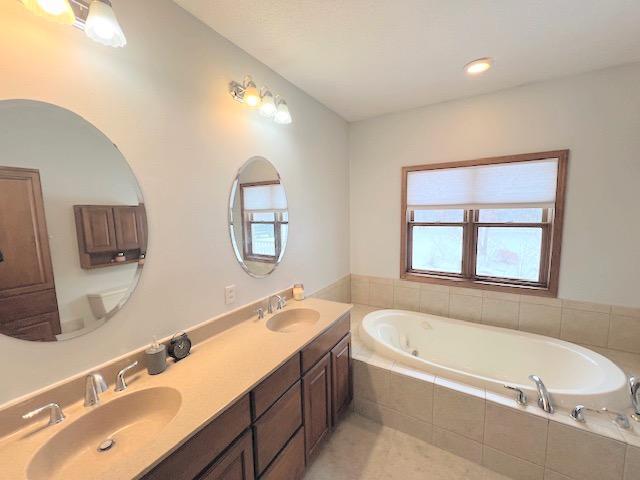 bathroom with vanity and a relaxing tiled tub