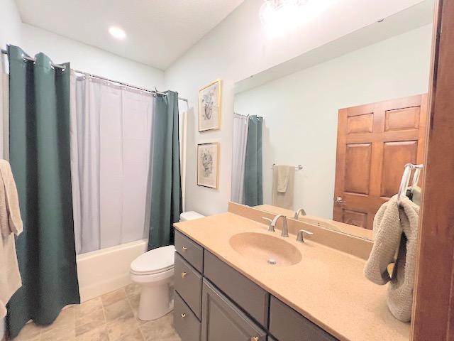 full bathroom featuring vanity, shower / bath combination with curtain, and toilet