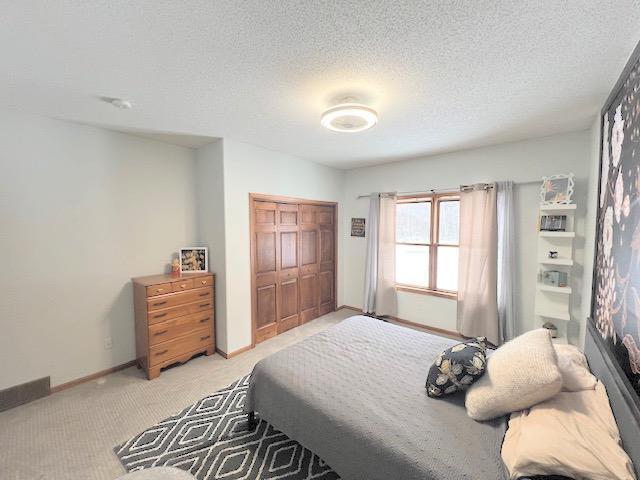 bedroom featuring light colored carpet, a textured ceiling, and a closet