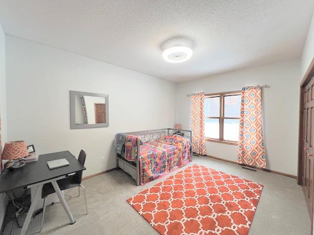 bedroom featuring light carpet and a textured ceiling