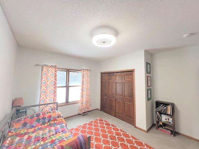 carpeted bedroom featuring a textured ceiling and a closet