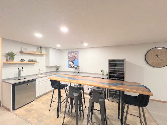 kitchen featuring white cabinetry, sink, stainless steel dishwasher, and light wood-type flooring