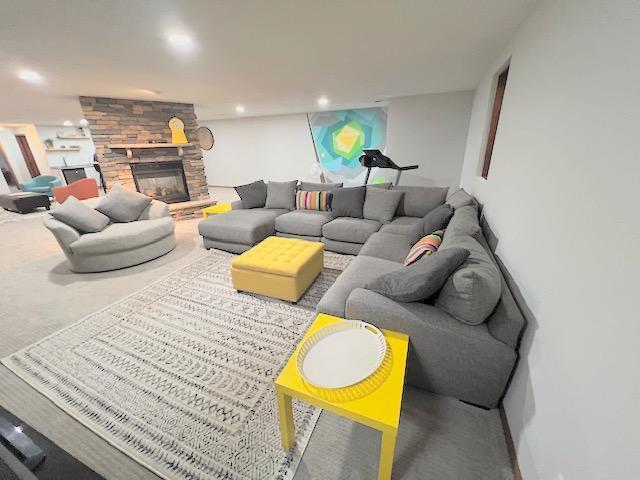 living room featuring a stone fireplace and carpet