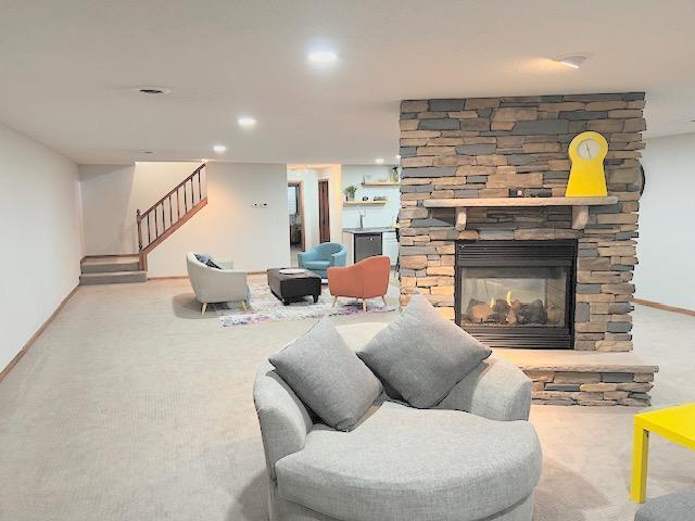 living room with carpet floors and a stone fireplace