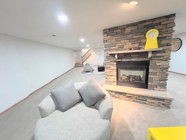 carpeted living room with a stone fireplace