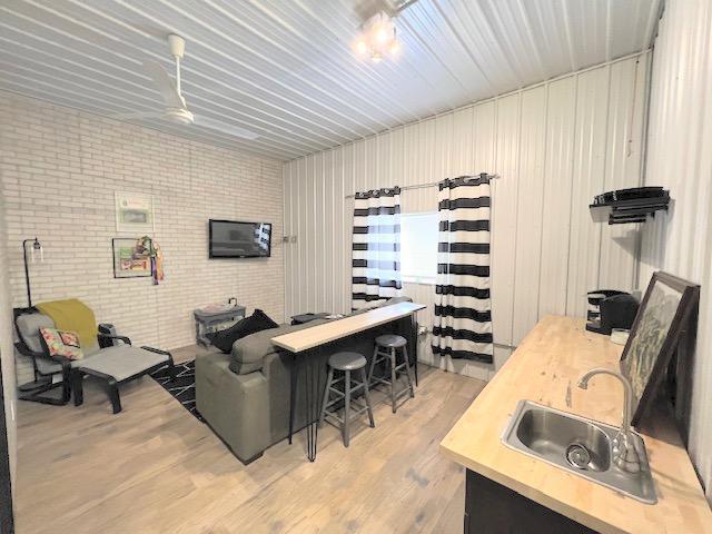 living room featuring sink, brick wall, and light hardwood / wood-style flooring