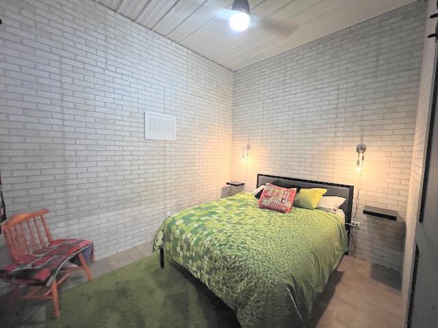 bedroom with ceiling fan and brick wall