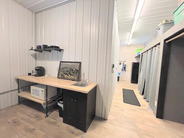 office with wood walls, light hardwood / wood-style flooring, and sink